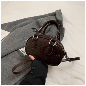 Détail du sac à main demi-cercle marron foncé avec motifs gaufrés et doubles poignées