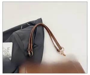 Detail of brown tote bag shoulder strap with gold metal rings and fine stitching
