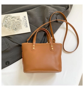 Détail d'un sac cabas en similicuir marron avec rivets dorés et bandoulière amovible
