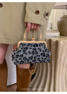 Detail of grey leopard print shell bag with golden metal handle and chain strap