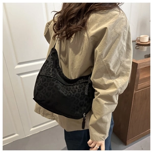 Detail of black leopard print nylon crossbody bag with textured animal pattern finish