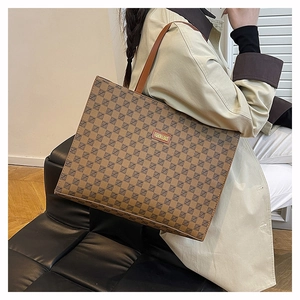 Detail of a brown plaid tote bag with faux leather label shown on a model's shoulder