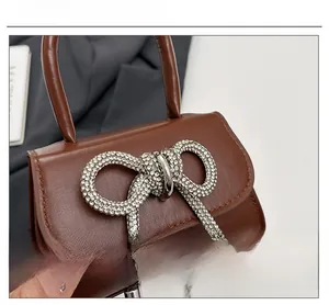 Détail du mini sac marron en cuir PU avec un grand nœud décoratif en strass argentés