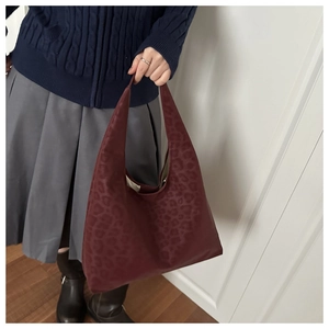 Close-up of deep red leopard print hobo tote bag held by a model in a casual setting