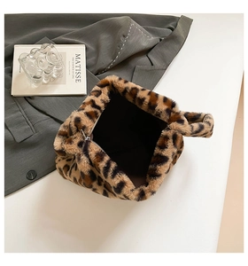 Detail of soft leopard print faux fur handbag next to a blazer and art book decor