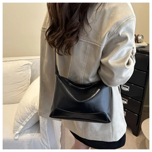 Detailed view of black glossy faux leather tote bag with elegant crescent stitching