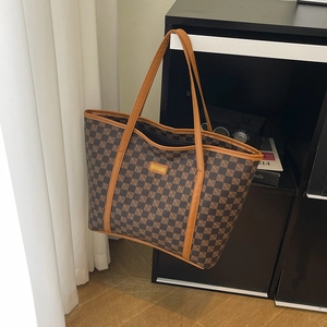 Classic brown plaid tote bag with leather handles and metallic fashion label displayed