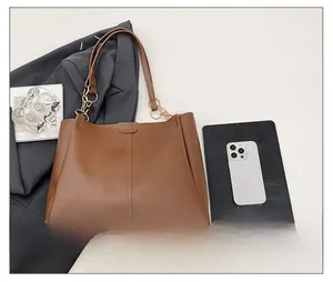 Detail view of brown PU leather tote bag with elegant golden metal rings and chain links