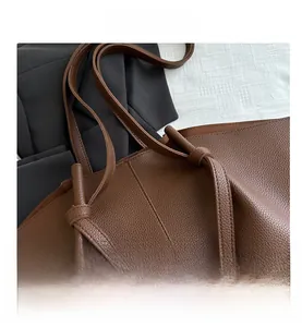 Detailed view of dark brown pebbled leather tote bag with unique shoulder strap knot design