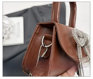 Détail de la boucle argentée et du nœud en strass sur le sac à main en cuir marron