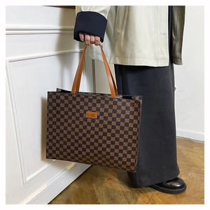 Detail of classic checkered tote bag featuring leather handles and brand logo tag