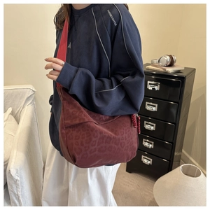 Detail view of burgundy leopard print hobo bag with wide strap and woven zipper puller