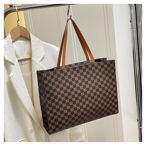 Close-up of brown checkerboard tote bag hanging on a rack with a white blazer