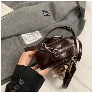 Détail du sac bandoulière vintage marron foncé en cuir brillant et finitions argentées