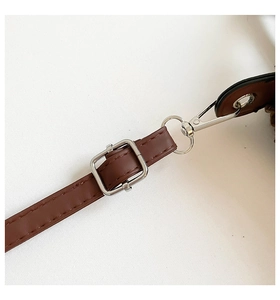 Detailed shot of dark brown leather shoulder strap with silver metal lobster clasp and buckle