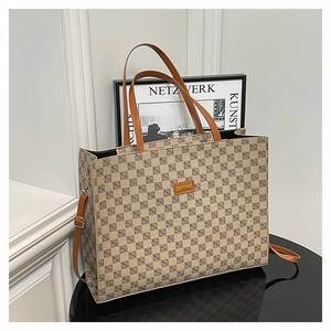 Detail of vintage tote bag featuring brown geometric pattern and leather shoulder strap