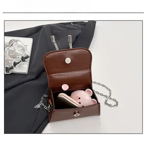 Vue détaillée du mini sac bandoulière marron montrant l'espace pour rouge à lèvres et maquillage