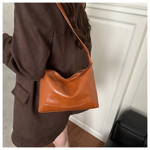 Detail showing smooth caramel glossy leather texture and zipper of the shoulder bag