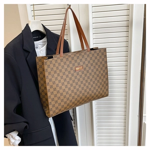 Macro detail of brown tote bag with geometric pattern and refined metal logo plaque