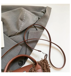 Detail view of brown faux shearling and leather trim on a stylish winter handbag