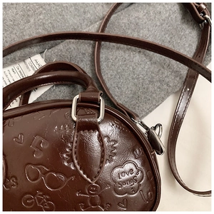 Détails du sac rond marron foncé avec motifs en relief 3D et texture en cuir de qualité