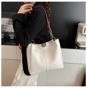 Detail of off-white large tote bag featuring brown leather strap and metal chain accents