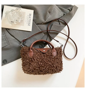 Detailed close-up of dark brown plush handbag with leather handles on grey background