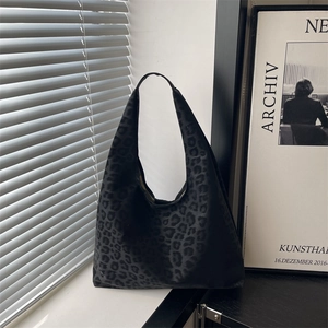 Matte black leopard print hobo tote bag with wide shoulder strap in natural lighting