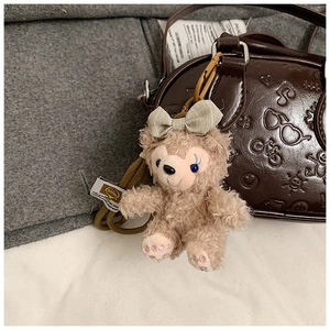 Détail d'un charme en peluche ShellieMay rose avec un nœud en lin sur un sac en cuir brun