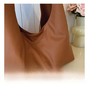 Detail showing smooth caramel brown leather texture and stitching of the large tote bag