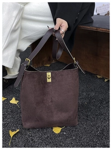 Détail d'un sac seau en daim marron foncé avec un fermoir rotatif doré de style rétro
