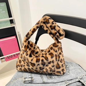 Faux fur leopard print shoulder bag with plush texture on denim clothing background