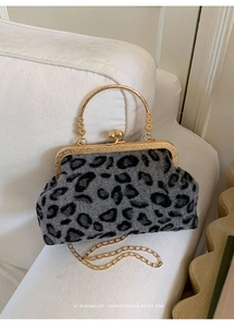 Detail of leopard print shell bag featuring vintage gold metal handle and plush texture