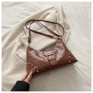 Detailed view of brown half-moon shoulder bag with silver studs and leather strap