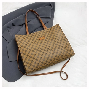 Detail of printed tote bag featuring brown geometric pattern and orange leather logo patch