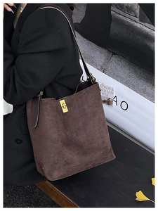 Détail d'un cabas en daim marron foncé avec boucle dorée sur un mannequin en automne