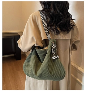 Detail of dark green corduroy tote bag with black and white striped shoulder strap