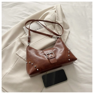 Detail of brown vintage PU leather tote with silver studs and buckle on blazer background