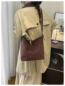 Détail d'un sac seau en daim marron foncé avec un fermoir rotatif en métal doré chic