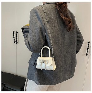 Gros plan détaillé du sac à main crème avec nœud en strass et bandoulière en chaîne