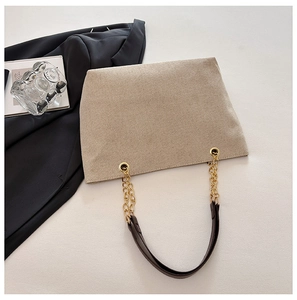 Detailed view of beige canvas tote with golden chain strap and brown leather accents