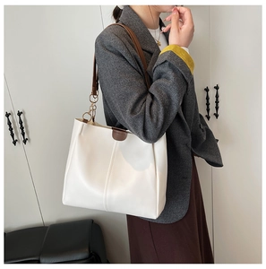 Detail of white leather tote bag featuring brown straps and elegant vertical stitching