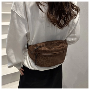 Close-up of leopard print waist bag worn by a model against a white staircase background