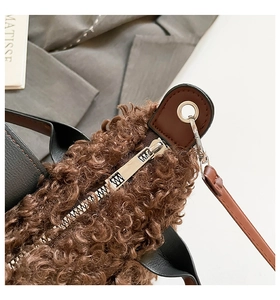 Detail of plush tan fleece handbag with silver zipper and black leather handle texture