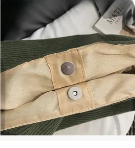 Close-up of green corduroy tote bag featuring dual silver magnetic snap button closures