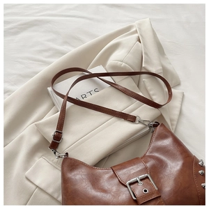 Close-up of brown vintage leather tote with silver rivets and metal buckle detail