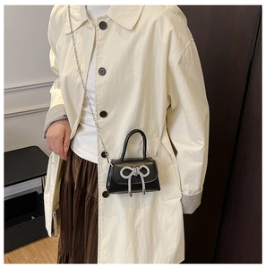 Mini sac à main noir avec nœud en strass et bandoulière chaîne sur le mannequin