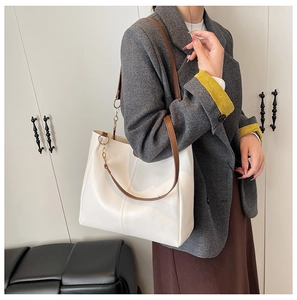 Detail of large beige tote bag with brown leather straps and gold metal ring hardware