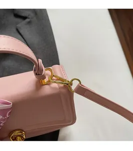 Detailed close-up of premium gold hardware and silk scarf on a pink leather handbag