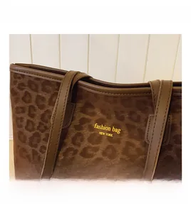 Detail of leopard print tote bag with brown straps and fine stitching on faux leather